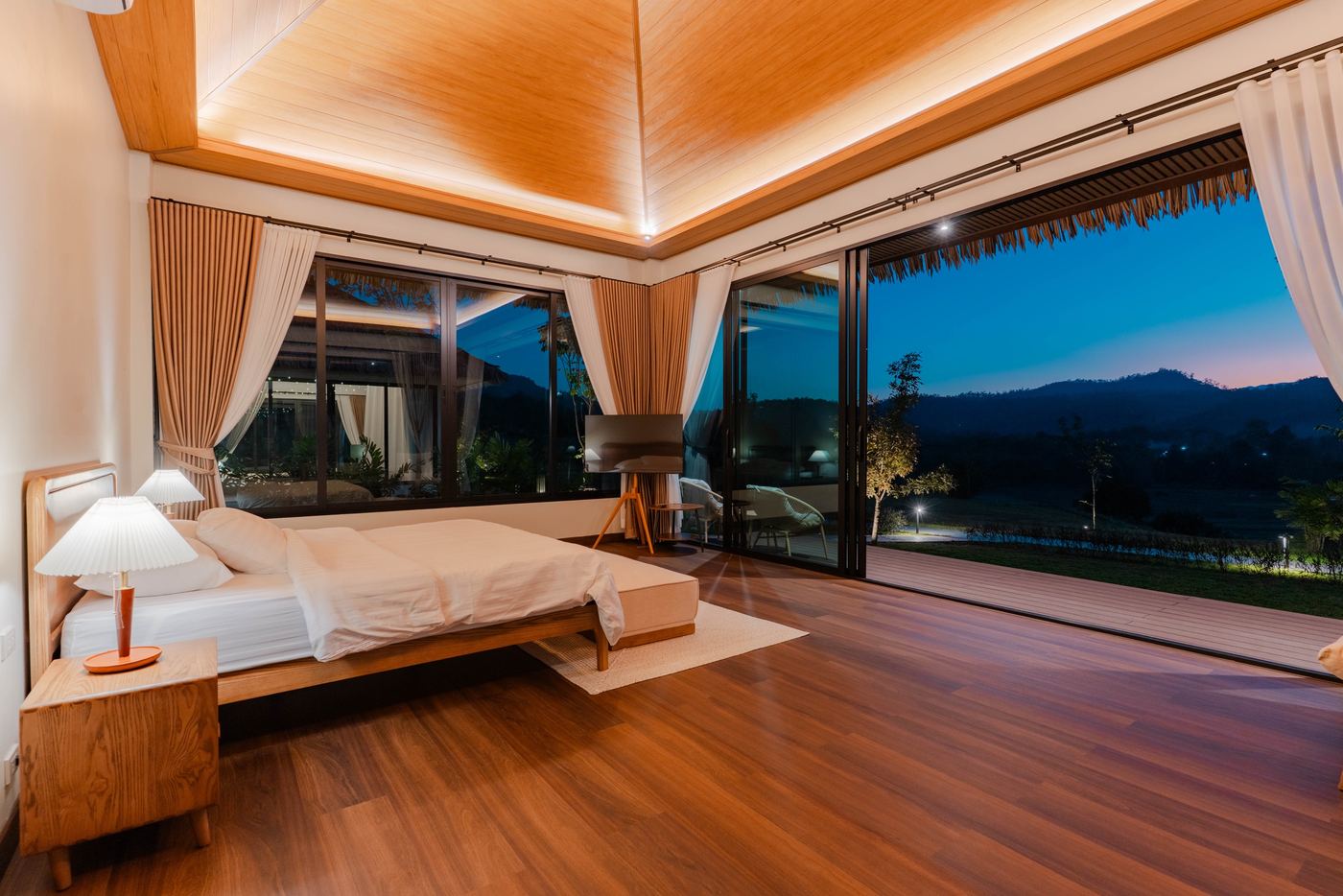 Bedroom at dusk with glass doors open to the mountains